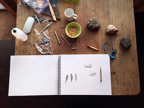 A table covered in drawing materials and a sketch pad