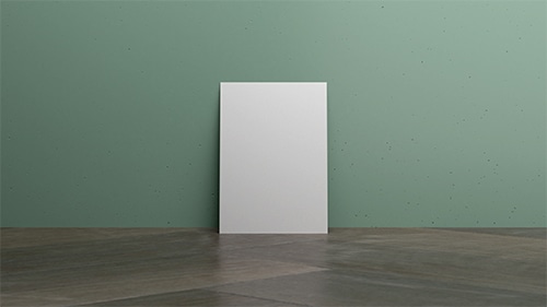 A piece of card leaning against a wall in a room with wooden floors and a green wall