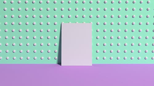 A piece of card leaning against a wall in a room with purple floors and a green wall