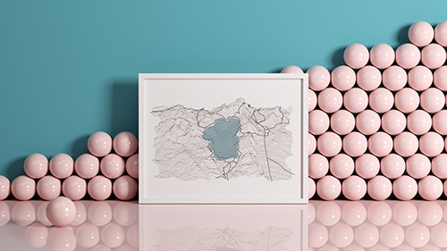 A map in a white picture frame leaning against a wall in a room with pink floors, a blue wall, and pink balls stacked against the wall