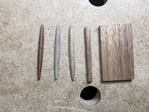 Wooden pegs lying on a table in their five stages of manufacture