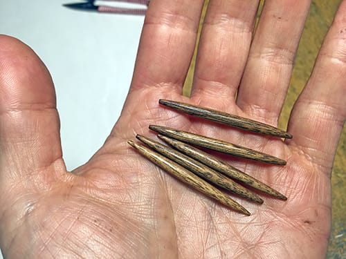 Five wooden pegs held in the palm of a hand