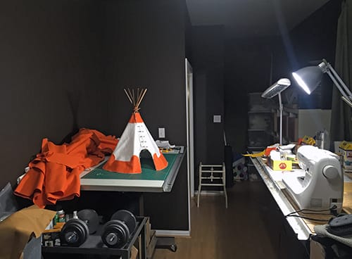 A room with a sewing machine and a home made tipi on a table