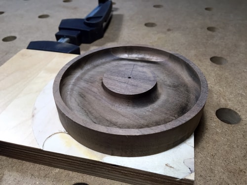 A circular piece of walnut with half of the inside cut out to form a kind of dish with an island of wood in the middle